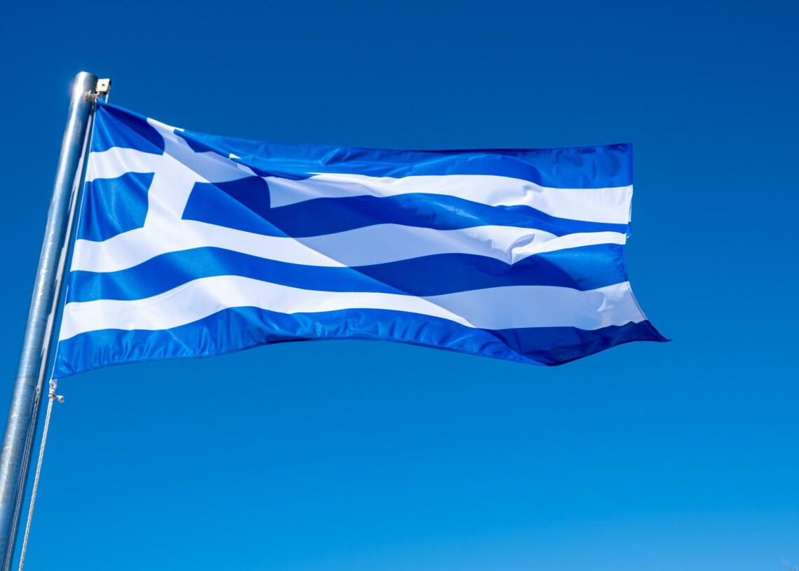Greek flag waving against blue sky background.